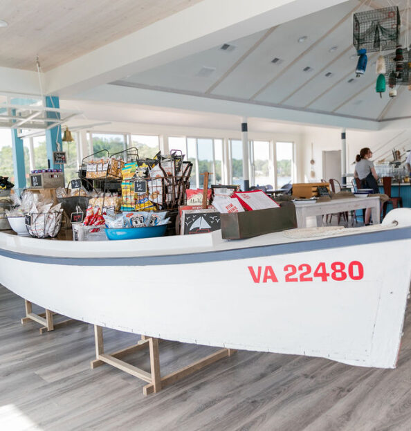 A white dingy on display inside a nautical style restaurant, displaying various snacks and souvenirs