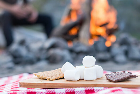 smore's ingredients on a table next to a campfire